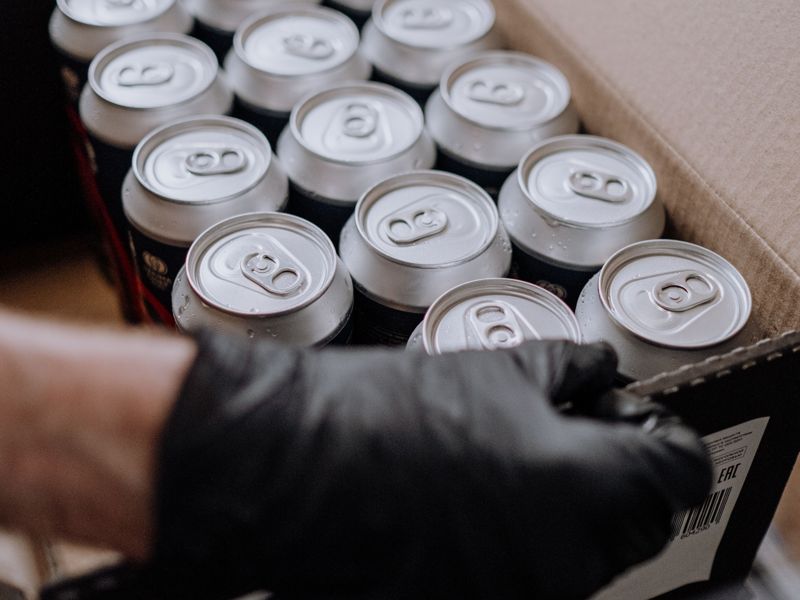 A gloved hand packing cans into a box