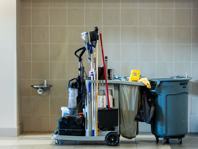 A commercial cleaning cart in a tiled corridor
