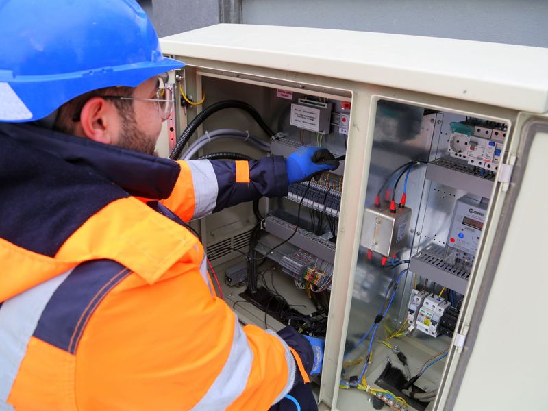An electrician in hi-vis working inside an open switchboard cabinet