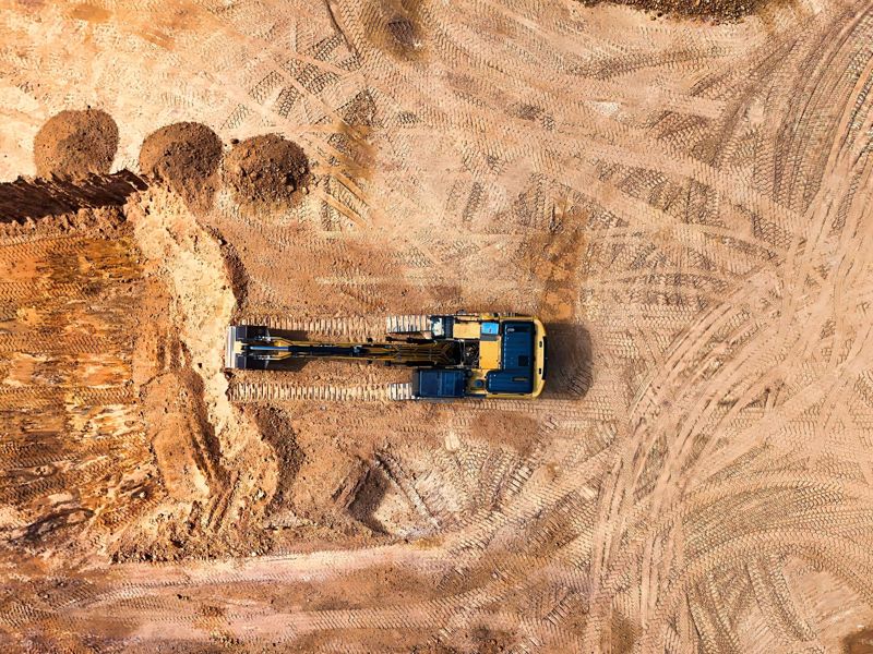 An excavator digging on an earthworks site, seen from above