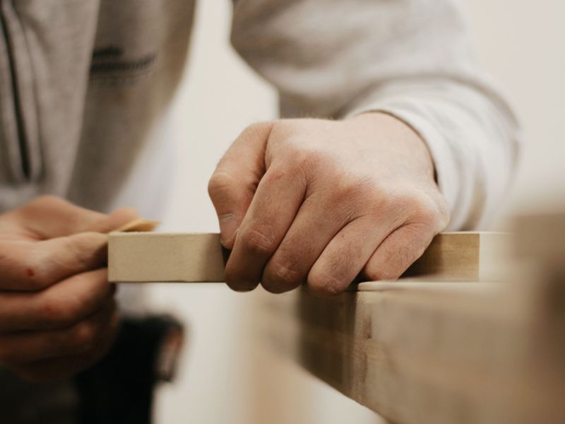 Hands shaping a piece of timber