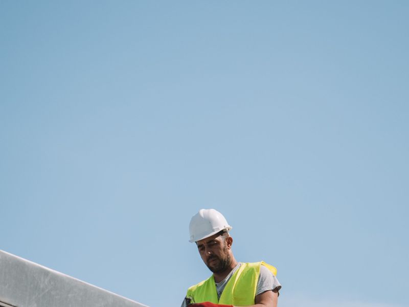 A construction worker in a hard hat and hi-vis against a clear sky