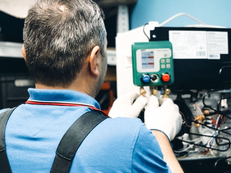 A technician checking a refrigeration unit with a gauge set