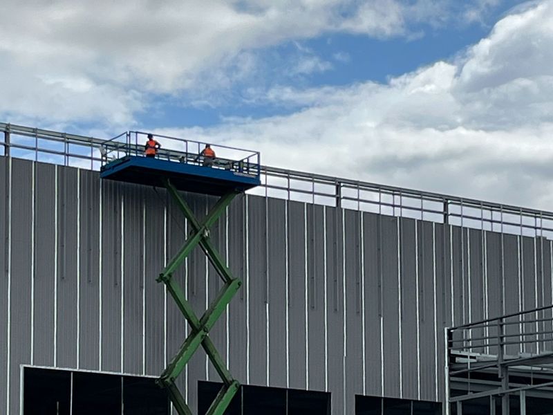 A scissor lift raised against a building’s cladding