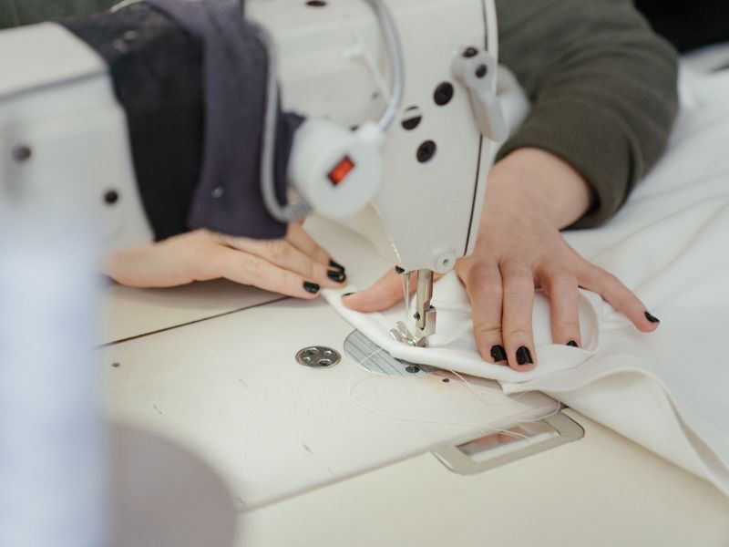 Hands guiding fabric through an industrial sewing machine