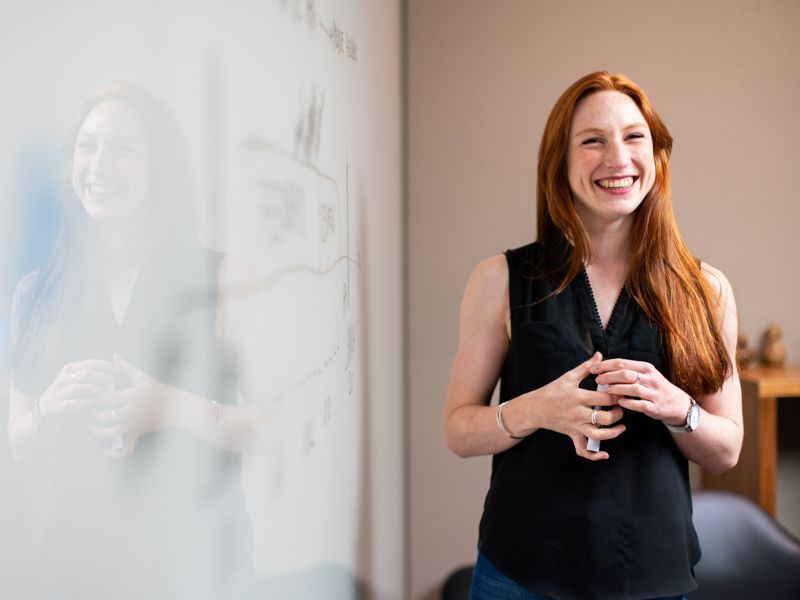 A trainer smiling beside a whiteboard