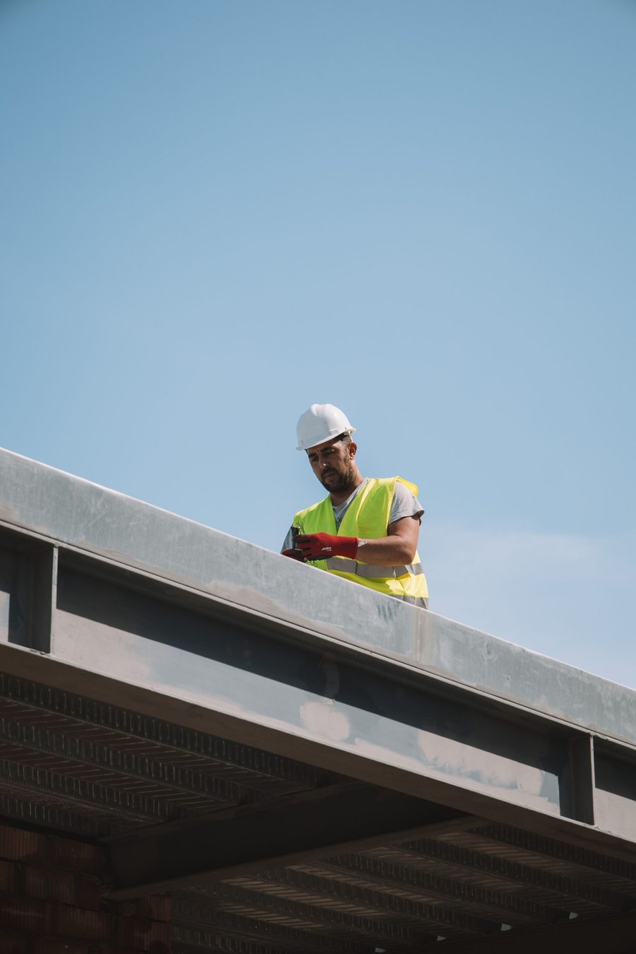 A worker in a hard hat, seen from below against the sky